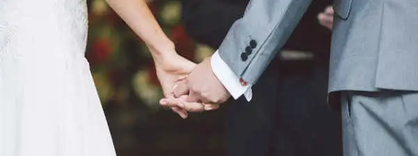 Two people holding hands at a wedding