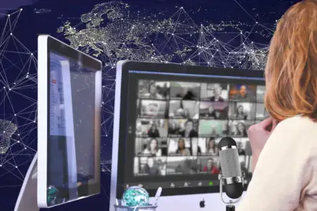 A woman with screens and a microphone before a map of the world