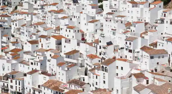 A hillside covered in White houses with red tiled roofs - Spanish translation