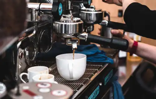 An espresso machine delivering coffee to a cup - Italian translation